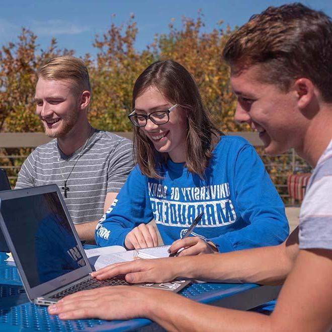 Three students studying together outside at table